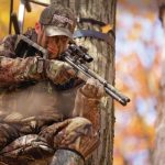 air rifle hunter in tree stand aiming at prey below.