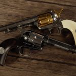 historical replicas. two colt single action army revolvers on a wood table.